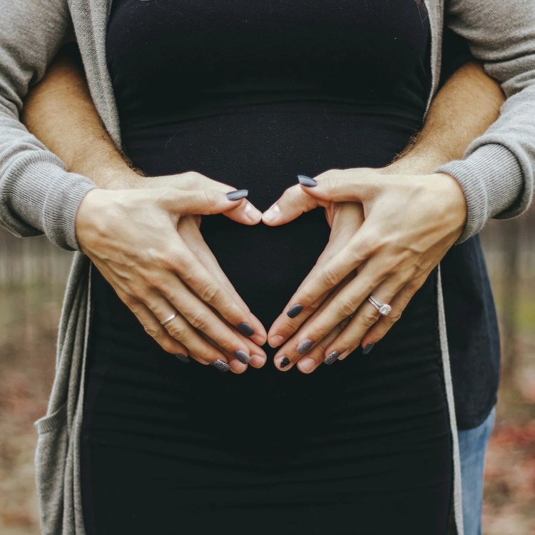 Hands forming a heart over a pregnant belly